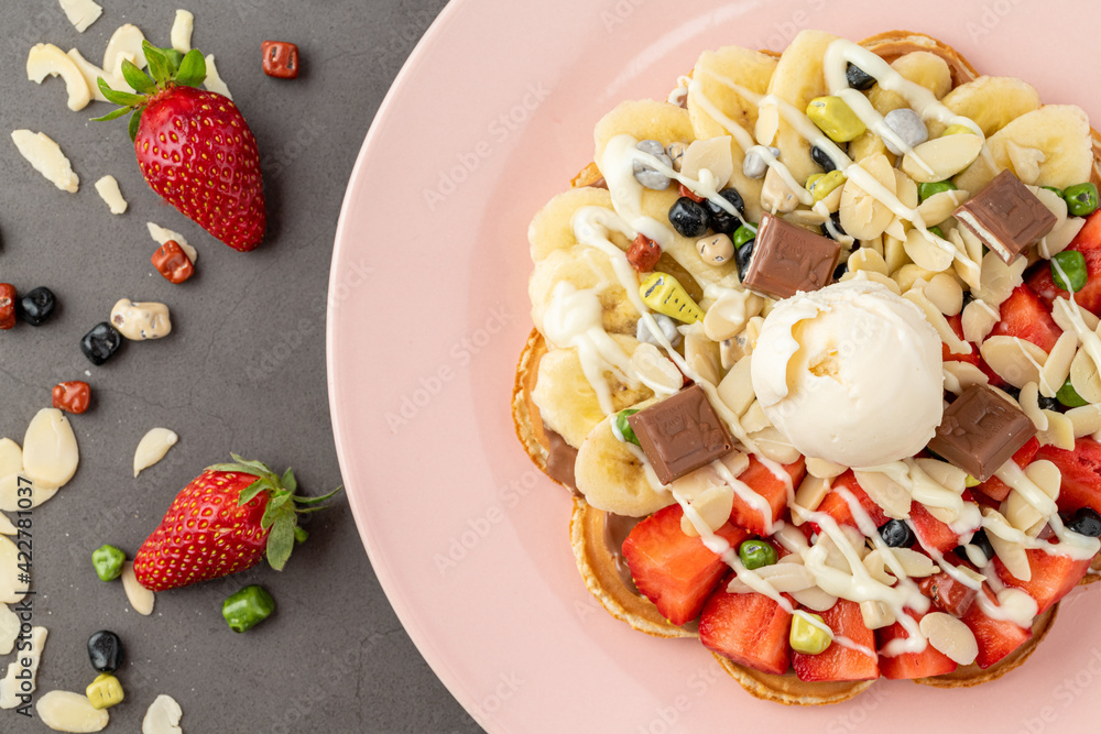 Heart waffle with banana and strawberry with gummy candy and ice cream on it. Heart waffle with banana and strawberry with gummy candy and ice cream on it.