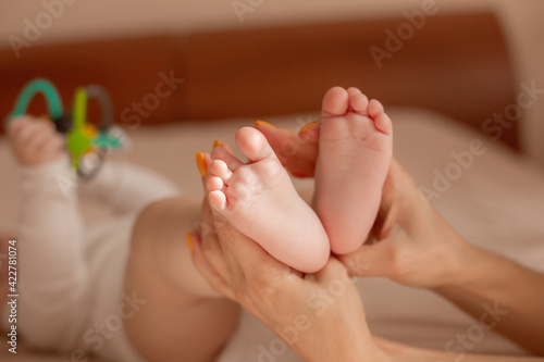 mom's hands hold the baby's legs