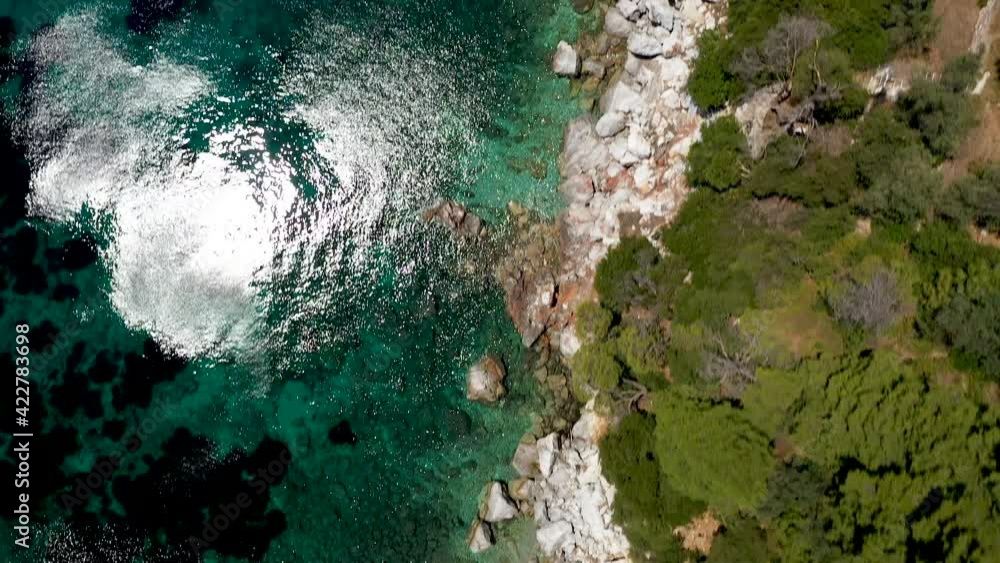 Aerial drone views over a rocky coastline, crystal clear Aegean sea waters, touristic beaches and lots of greenery in Skopelos island, Greece. A typical view of many similar Greek islands. Aerial drone views over a rocky coastline, crystal clear Aegean sea waters, touristic beaches and lots of greenery in Skopelos island, Greece. A typical view of many similar Greek islands.