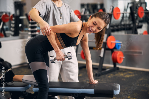 Joyful sportswoman lifting dumbbell during her training
