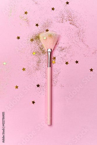 Festive magic make up brush on pink background.