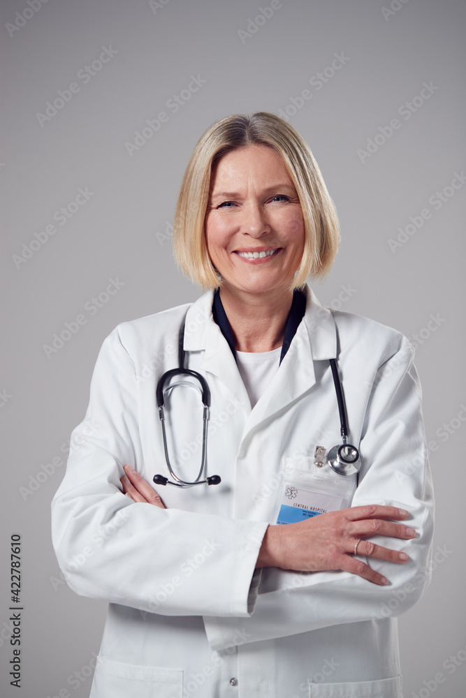 Studio Portrait Of Smiling Mature Doctor Wearing White Coat Against Plain Background Studio Portrait Of Smiling Mature Doctor Wearing White Coat Against Plain Background