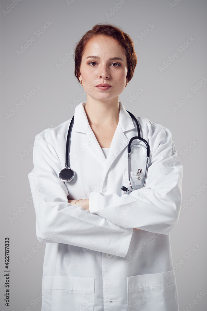 Studio Portrait Of Serious Young Female Doctor Wearing White Coat Against Plain Background Studio Portrait Of Serious Young Female Doctor Wearing White Coat Against Plain Background
