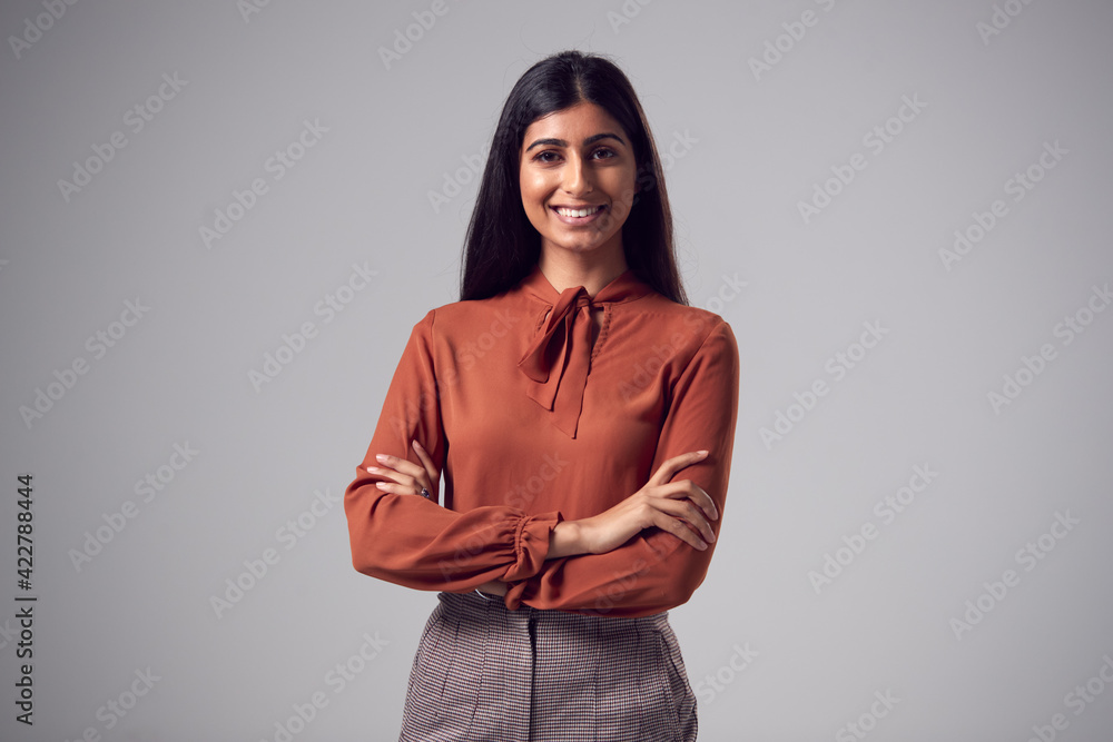 Studio Portrait Of Smiling Young Businesswoman With Folded Arms Against Plain Background Studio Portrait Of Smiling Young Businesswoman With Folded Arms Against Plain Background