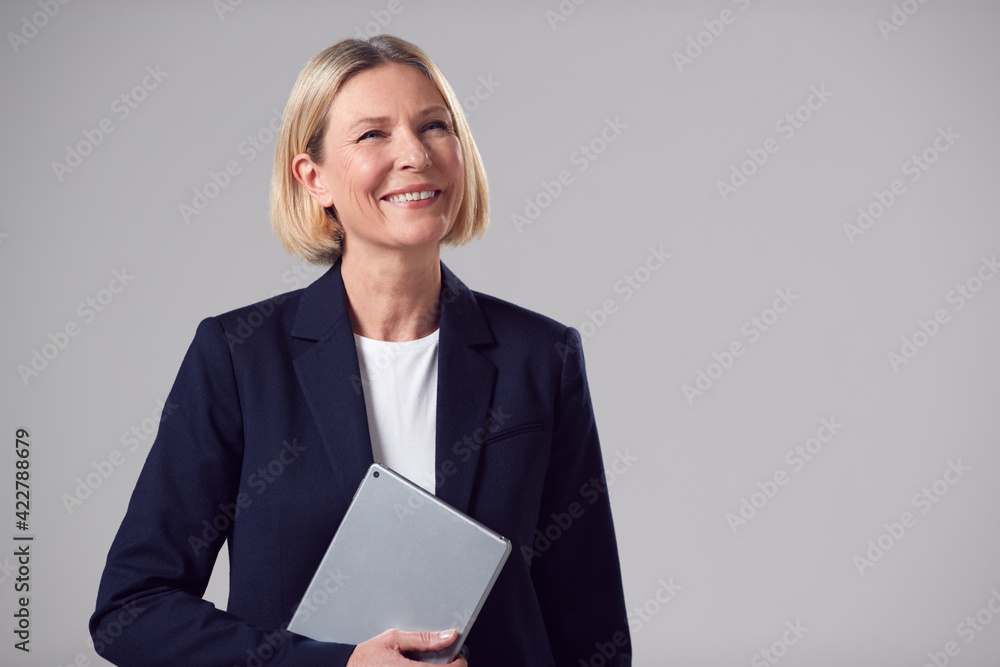 Studio Portrait Of Smiling Mature Businesswoman Holding Digital Tablet Against Plain Background Studio Portrait Of Smiling Mature Businesswoman Holding Digital Tablet Against Plain Background