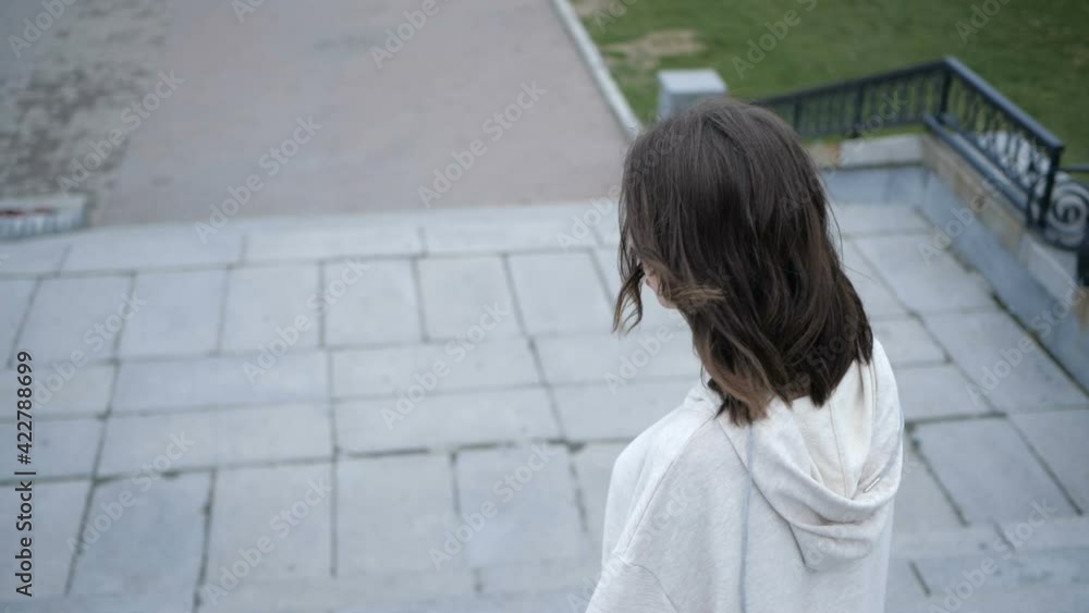 A young beautiful girl with brown hair walks around the city going down the stairs and turns on camera. High quality FullHD footage A young beautiful girl with brown hair walks around the city going down the stairs and turns on camera. High quality FullHD footage
