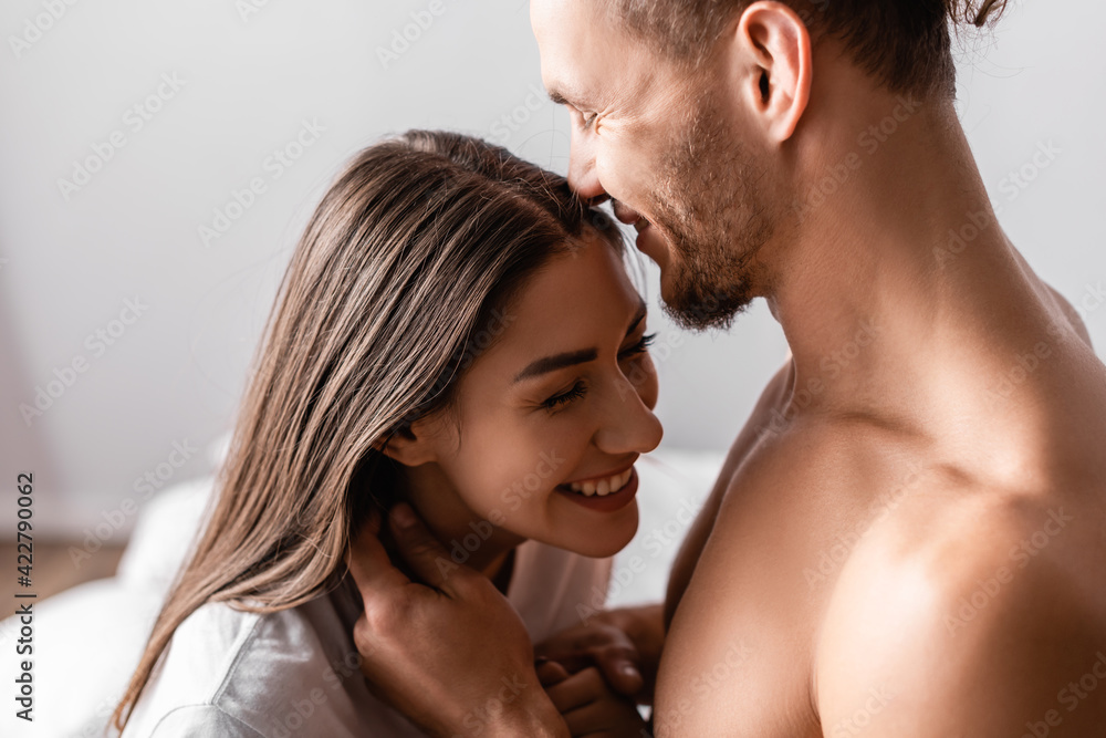 Muscular man smiling while touching pretty girlfriend at home Muscular man smiling while touching pretty girlfriend at home
