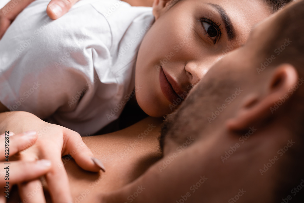 Young woman looking at shirtless boyfriend on blurred foreground Young woman looking at shirtless boyfriend on blurred foreground