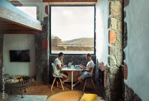 Two man working from their home  in a remote place in the countryside - Beautiful gay couple teleworking from a luxury yet cozy chalet