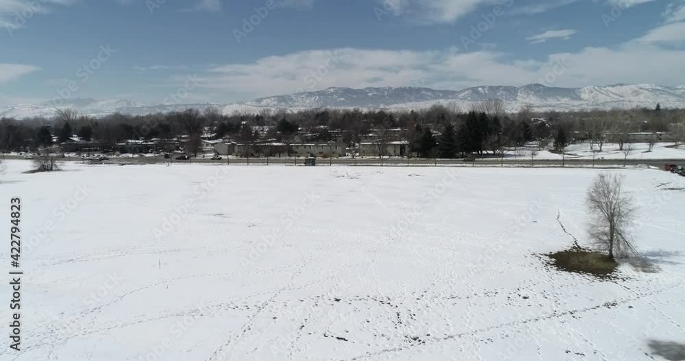 A flight above a snowy field in Fort Collins Colorado March 2021 after historic snow storm. Rocky mountains in the back. A flight above a snowy field in Fort Collins Colorado March 2021 after historic snow storm. Rocky mountains in the back.