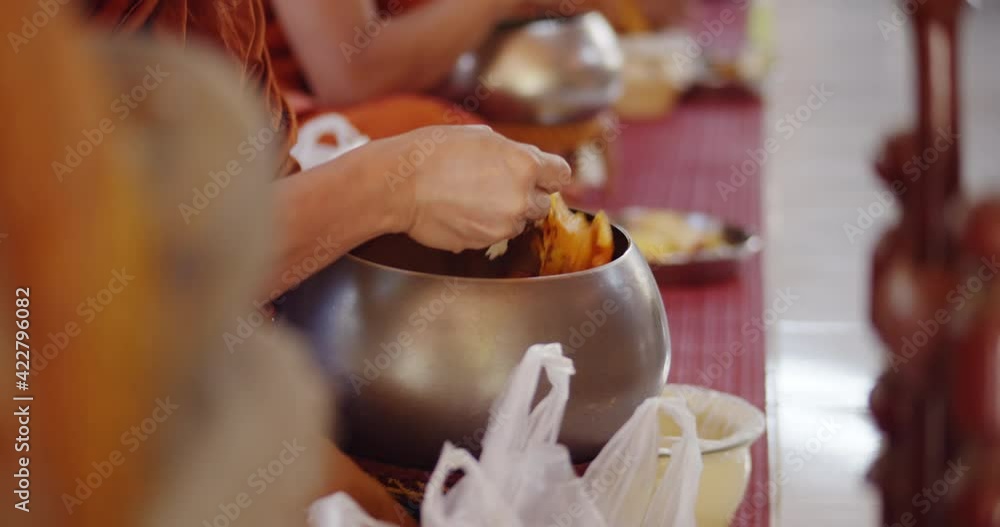 The Buddhist monks scoop the foods in their alms bowls to eat after the people made merit at the Buddhist temple in the forest, Thailand, southeast Asia.