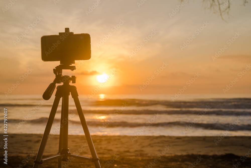 silhouette phone on tripod during record vdo and photo beach with sunrise and sea background silhouette phone on tripod during record vdo and photo beach with sunrise and sea background