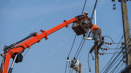 Electrician working on poles to install high-voltage equipment.