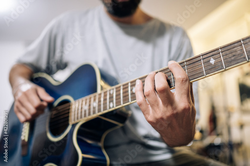 Young man practicing acoustic guitar at home.Focus selective