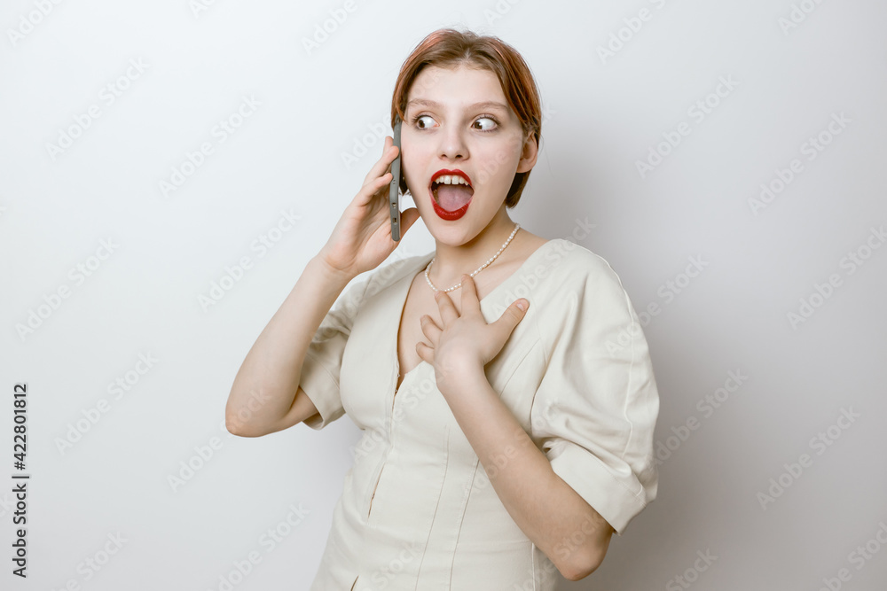 The happy woman learned the good news on her mobile phone. Light background The happy woman learned the good news on her mobile phone. Light background