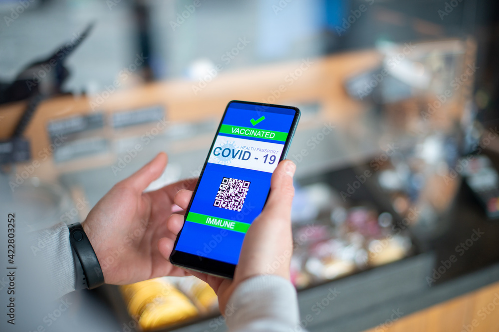 Man showing on smartphone covid imune certificate wich allow him to buy goods Man showing on smartphone covid imune certificate wich allow him to buy goods