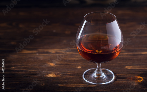 Glass of cognac or brandy on natural wooden background. Glass of whiskey. Alcohol drink on Bar counter in the restaurant. Macro close-up with copy space. 