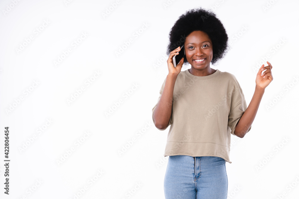 Cropped portrait of a funny young african girl talking emotionally on phone isolated over white background Cropped portrait of a funny young african girl talking emotionally on phone isolated over white background