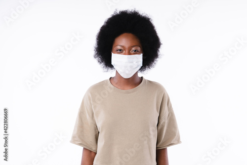 Confident afro girl in medical mask against Covid 19 isolated over white background © InsideCreativeHouse