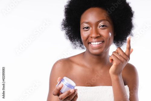 Smiling african girl with face cream in spa towel isolated in white background