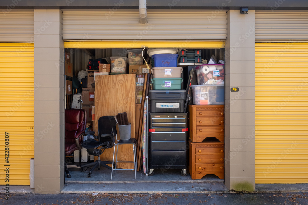 Contents of a house packed into a storage unit with the door open Stock