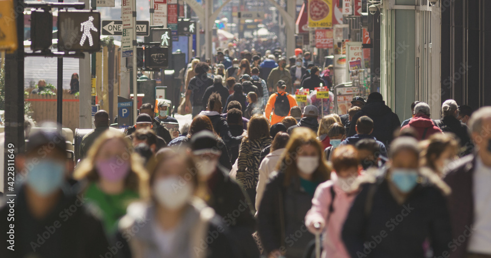 Anonymous crowd of people walking street wearing masks during Covid 19 pandemic in New York City