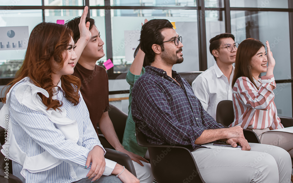 Fototapeta premium Group of people raising their hands and attending seminar