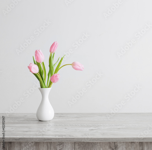 Wallpaper Mural pink tulips in white ceramic vase on wooden table on background white wall Torontodigital.ca