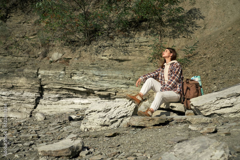 Happy woman sitting on stone and enjoying sunny weather Happy woman sitting on stone and enjoying sunny weather