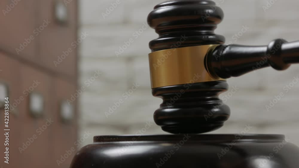Close-up of a judge hitting a block with a hammer in a courtroom. Close-up of a judge hitting a block with a hammer in a courtroom.