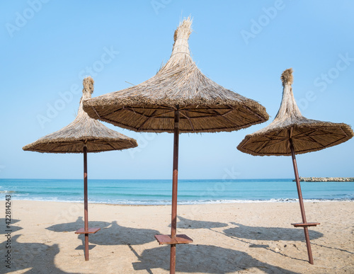 Summer landscape with straw umbrellas on the beach in Mangalia or Mamaia. Beach at the Black Sea in Romania.