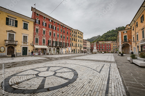 Cityscape. Carrara city center: Piazza Alberica with the commemorative monument in the center and the Ducal Palace , and small open doors cafes, shops in Tuscany, Italy photo