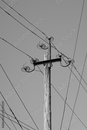 Old electrical pole with plugs and wires in sky background. BW photo