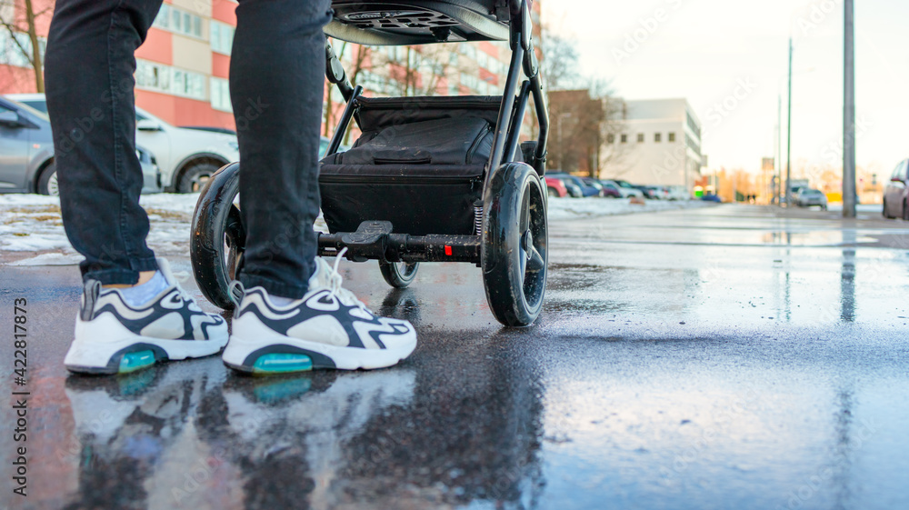 Fototapeta premium mom walks on the street with a baby in a stroller, stroller close-up, bottom view