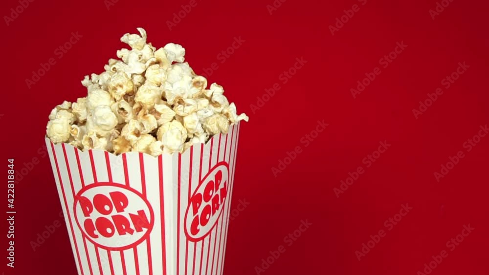 Full popcorn in a classic popcorn box on a red background.Popcorn