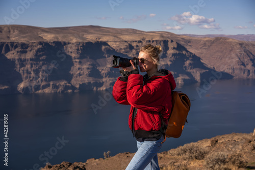 Female traveler taking picture while standing at cliff with wonderful scenery of river