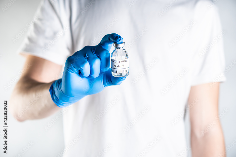 The doctor holds coronavirus vaccine in his hand. He has blue rubber gloves on his hands, which serve as protection against coronavirus infection. The doctor holds coronavirus vaccine in his hand. He has blue rubber gloves on his hands, which serve as protection against coronavirus infection.