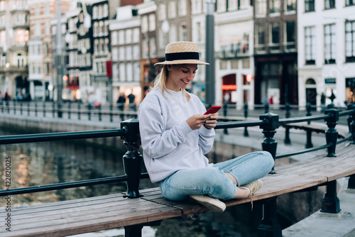 Canvas Print Young woman sitting on bench and using smartphone