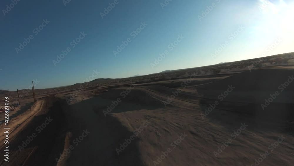 At an off-road race track in the Mojave Desert, a racing drone flies over the dunes where vehicles will clash in competition At an off-road race track in the Mojave Desert, a racing drone flies over the dunes where vehicles will clash in competition