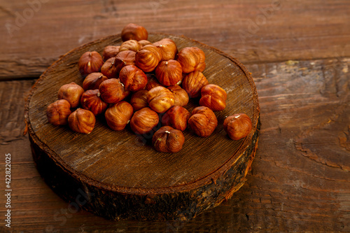 Hazelnuts scattered on a wooden round board on the table.