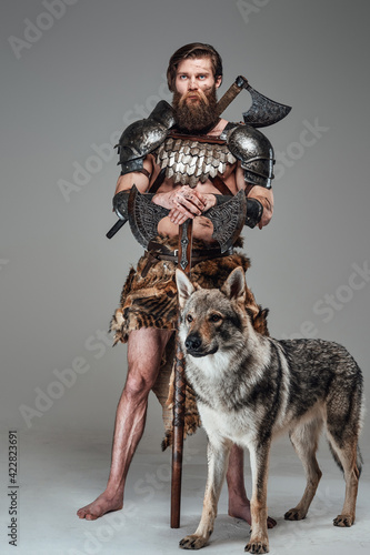 Grimy barbaric viking with nude body posing with beautiful wolf