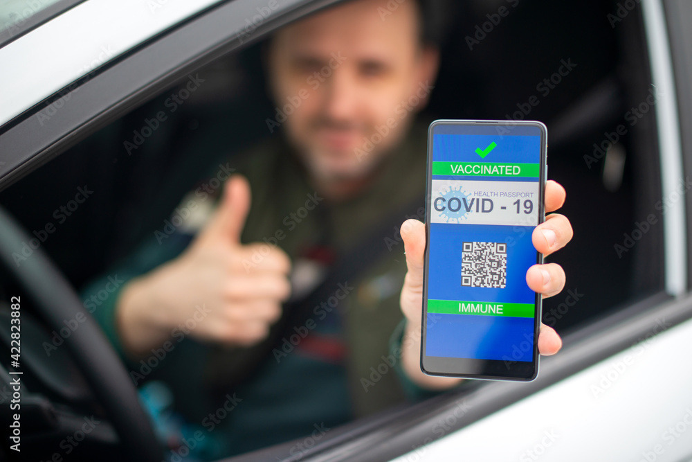 Man showing vaccine passport on his phone while he is in his car.