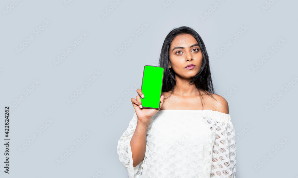 Portrait of an Asian woman showing green blank screen mobile phone isolated over gray background, advertising purpose. Portrait of an Asian woman showing green blank screen mobile phone isolated over gray background, advertising purpose.