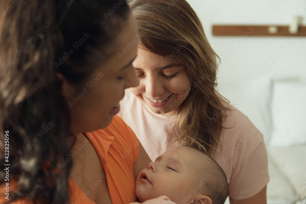 lesbian couple looking at sleeping baby in the living room. lesbian couple looking at sleeping baby in the living room.