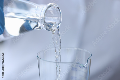 Pure water is poured from a bottle into transparent glass