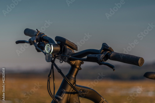 Black and gray electric bicycle in sunrset evening time on color field