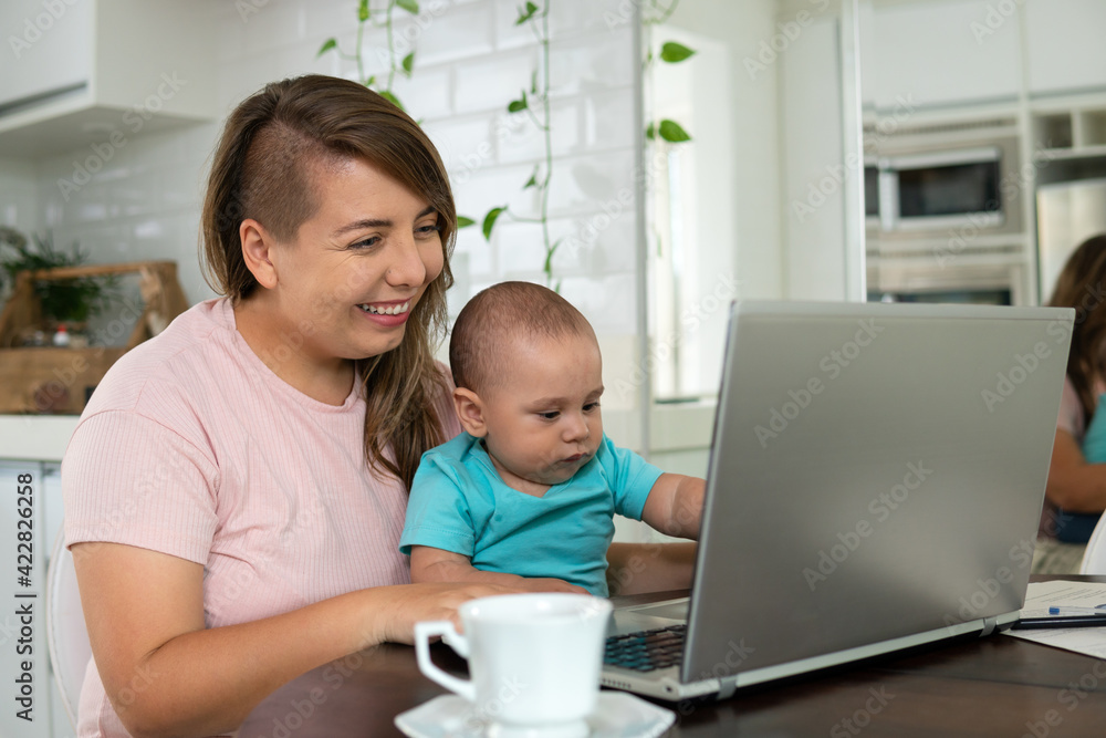 young mother doing home office and working in laptop with baby.