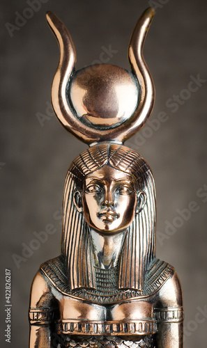 The figure of the Egyptian goddess Isis on a brown corduroy background. Bronze statuette.