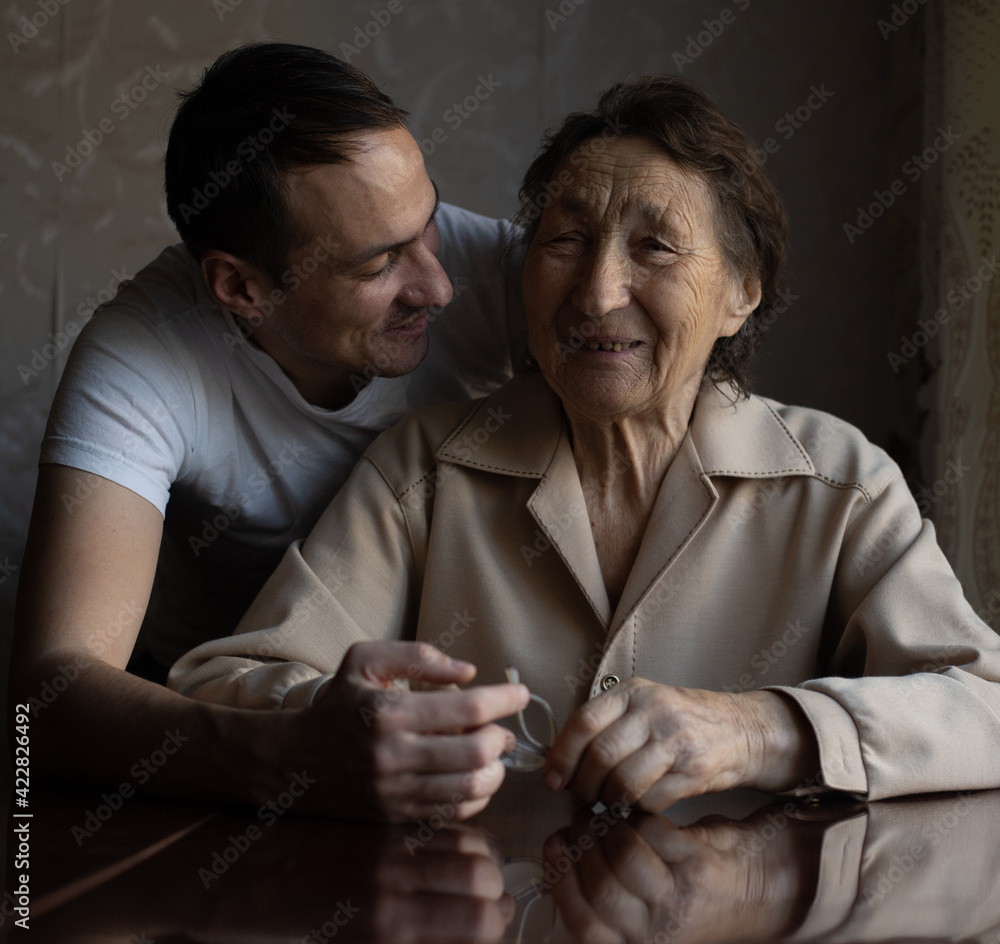 a very old woman and an adult grandson a very old woman and an adult grandson