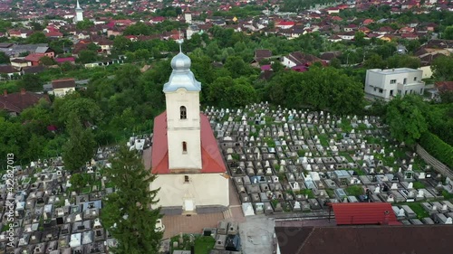 Hunedoara, Romania, July 28, 2019. Aerial of Reformed Church Biserica Reformata and old cemetery, located near the famous landmark Corvin Castle, 1644 year carved on the roof photo